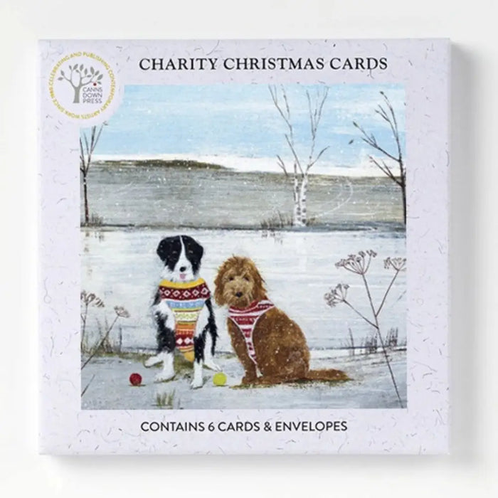 A charity christmas card pack by hannah cole featuring two dogs in festive sweaters on a snowy background