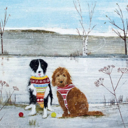 A cozy winter scene with two dogs wearing colorful christmas jumpers on a hannah cole christmas card pack