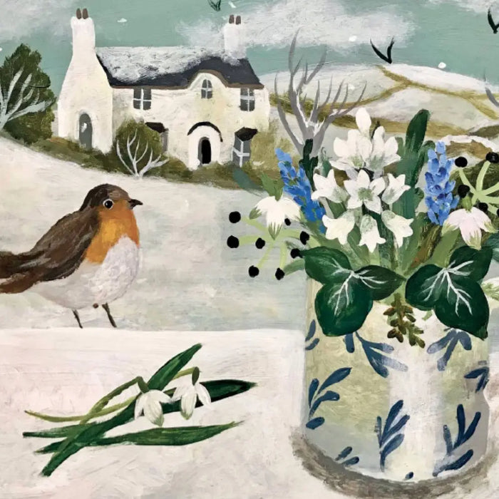 A white ceramic vase with blue leaf patterns holds white and blue flowers for snowy owl christmas cards by sarah bowman