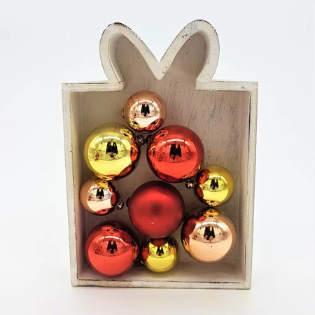 A collection of shiny red gold and rose gold metallic christmas baubles in a white wooden gift box with two designs