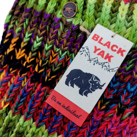 A colorful hand-knitted beanie with rainbow wool yarns and black yak brand tag paired with a fair trade wool scarf