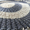 Circular seagrass rug with dark gray and beige braided rope in concentric rings made of natural fibers
