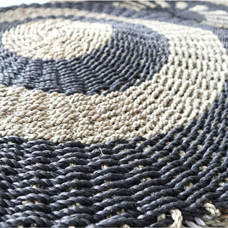 Circular seagrass rug with dark gray and beige braided rope in concentric rings made of natural fibers