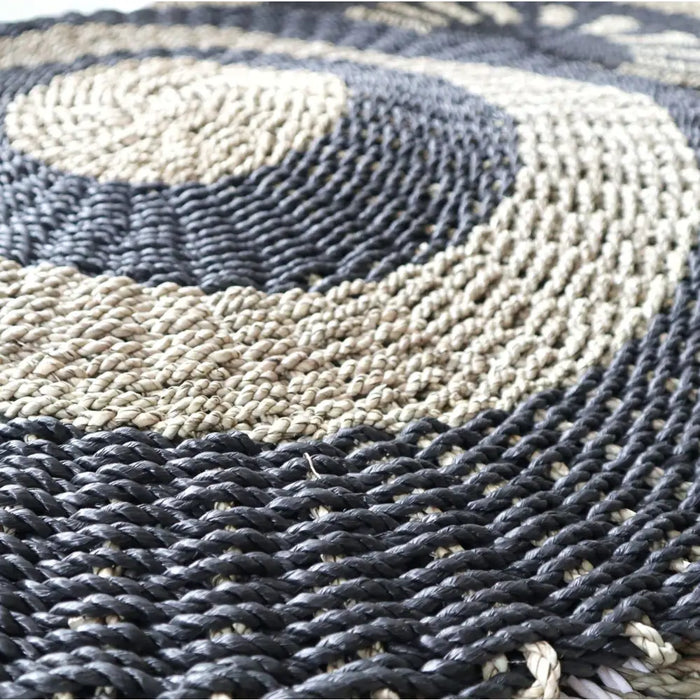 Circular seagrass rug with dark gray and beige braided rope in concentric rings made of natural fibers