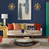 Beige upholstered sofa with red and patterned throw pillows on a natural and black circular seagrass rug