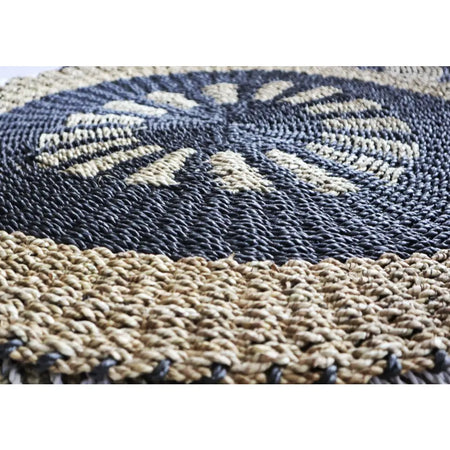 Handcrafted circular seagrass rug with dark gray and beige woven radial patterns made from natural fiber