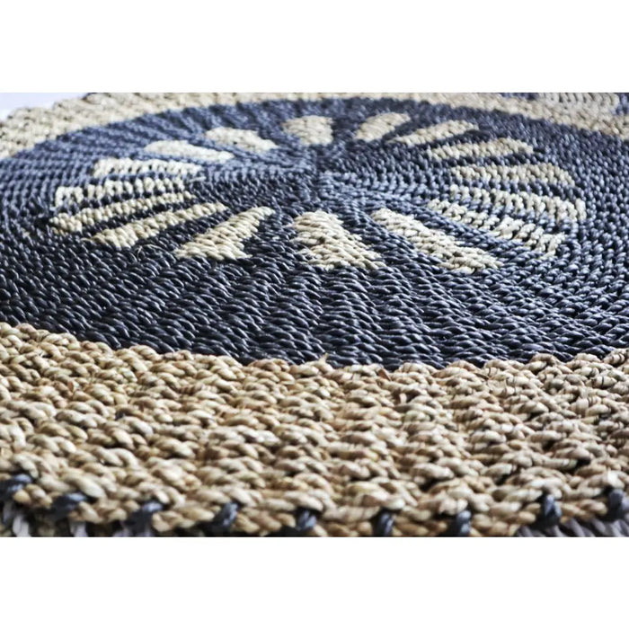 Handcrafted circular seagrass rug with dark gray and beige woven radial patterns made from natural fiber