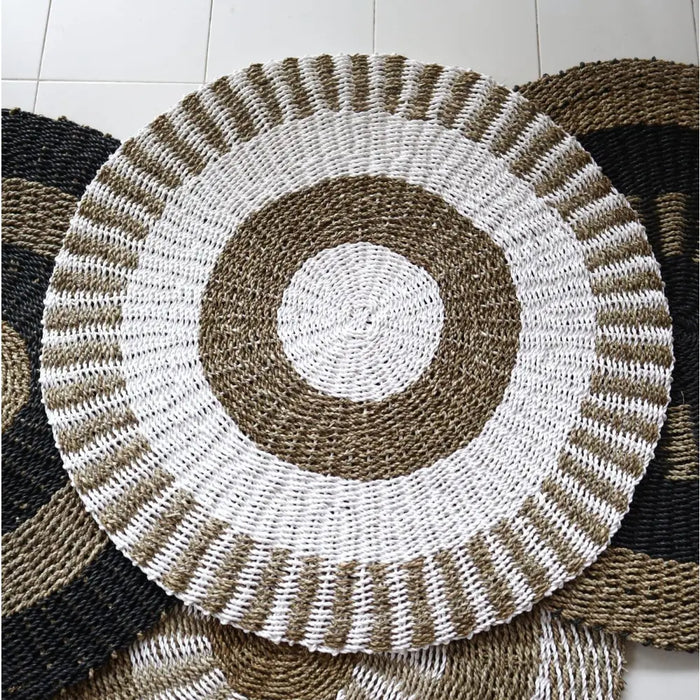Circular seagrass rug with concentric rings of white and natural brown fibers made from woven seagrass