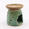 A green ceramic oil burner with leaf cutouts and a brown rimmed dish on top, classic oil burner blue style