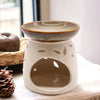 Classic oil burner in glazed white ceramic with leaf cutouts and brown rim on top dish for essential oils