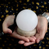 A smooth white usb crystal rock himalayan salt lamp with a textured beige stone base showing its hygroscopic properties