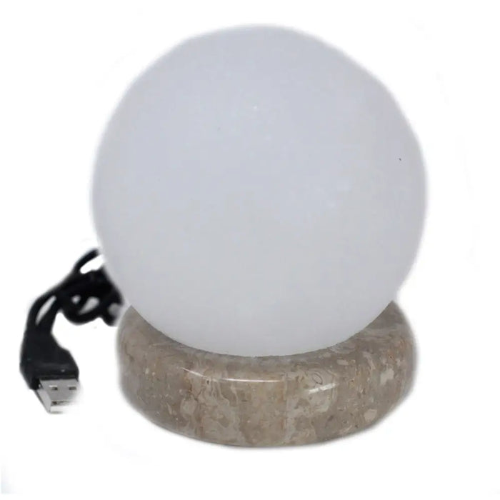 A sleek frosted white himalayan salt lamp ball with a textured beige stone base and black usb crystal rock cable