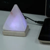 A glowing white himalayan salt lamp pyramid with usb crystal rock and a pinkish hue showing its hygroscopic properties