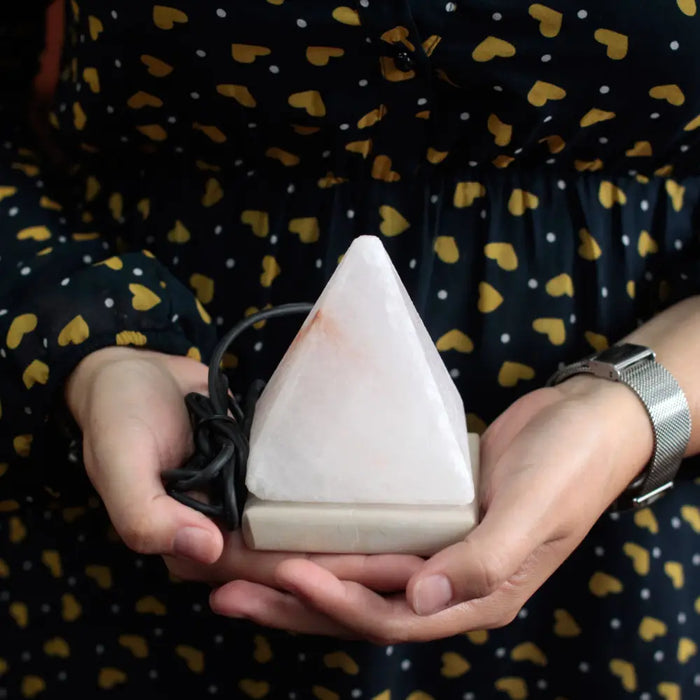 A white triangular usb crystal rock himalayan salt lamp with smooth translucent surface and black cord attached