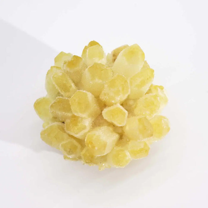 A cluster of translucent yellow natural quartz with faceted geometric shapes in a coloured quartz cluster display