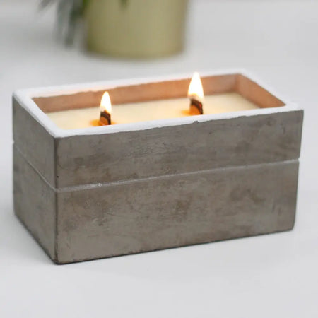Gray concrete rectangular candle box with two lit candles in spiced south sea lime scent