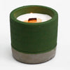 Concrete candle pot in green with white wax candle and wooden wick showing sea moss and herbs scent