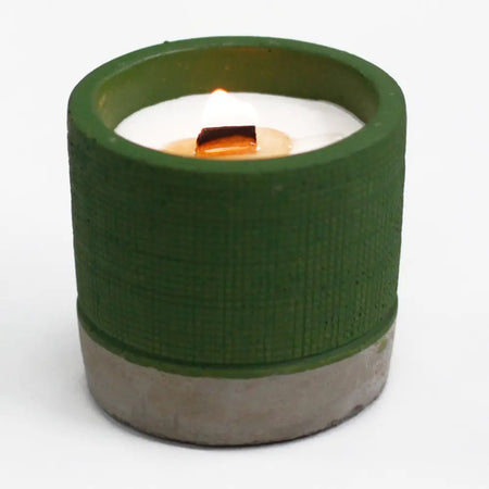 Concrete candle pot in green with white wax candle and wooden wick showing sea moss and herbs scent