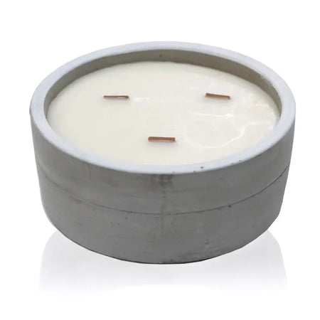 A sleek gray concrete bowl candle with three wooden wicks and creamy white wax for a patchouli and dark amber scent