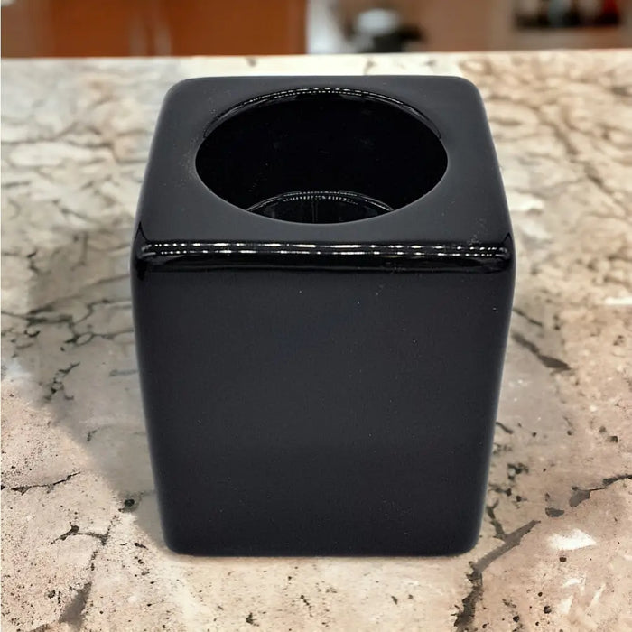 A contemporary black square ceramic tealight holder with a glossy finish and a circular opening on top