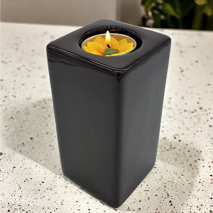 Contemporary brown square ceramic tealight holder with a lit yellow flower-shaped ceramic tealight inside