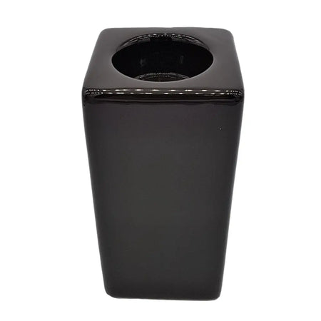 Black glossy ceramic tissue box with square shape and circular opening next to brown ceramic tealight holder tall