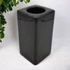 Black glossy ceramic square trash can with circular opening next to a tall contemporary brown ceramic tealight holder