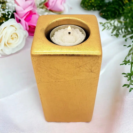 Contemporary gold square ceramic tealight holder with textured metallic finish holding a white 5cm square candle