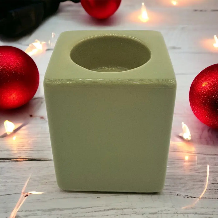 A matte sage green ceramic tealight holder with a smooth rounded interior in a cube shape high x 7cm