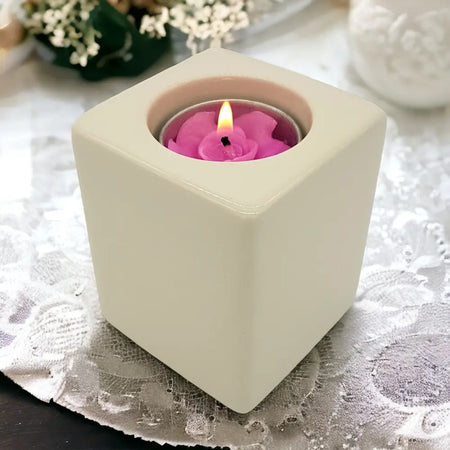 Contemporary ivory square ceramic tealight holder with a lit pink rose-shaped ceramic tealight inside