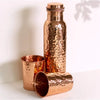A hammered copper water bottle with matching lid and two cups gift set in warm metallic sheen for warm water use
