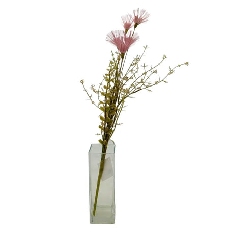 A clear rectangular glass vase holding dusky pink artificial wild flowers with fluffy petals and slender green stems
