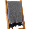 A navy cotton comfort throw with a white herringbone zigzag pattern and dark tassels along the edges