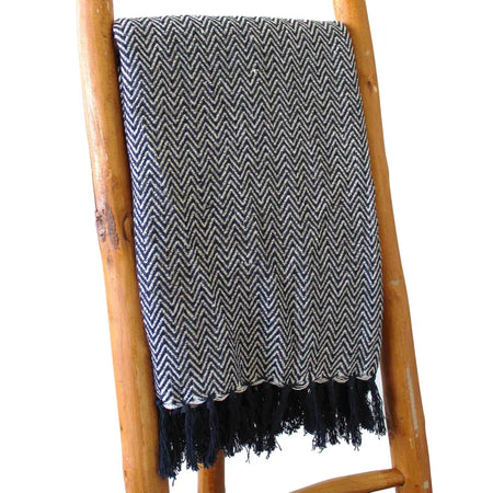 A navy cotton comfort throw with a white herringbone zigzag pattern and dark tassels along the edges