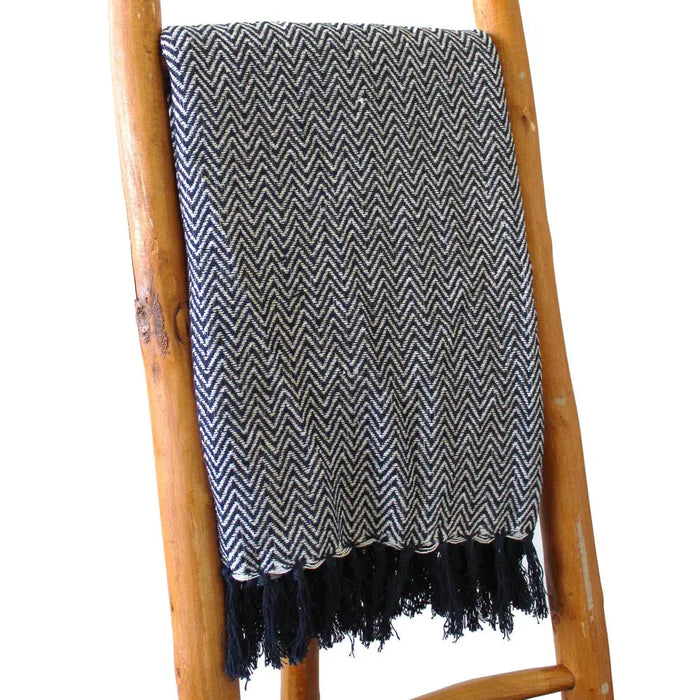 A navy cotton comfort throw with a white herringbone zigzag pattern and dark tassels along the edges