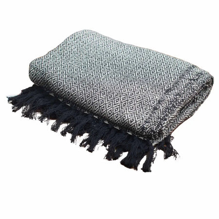 A folded black and white geometric cotton comfort throw with dark fringed edges, a versatile piece for any space