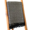 A textured black and gray cotton comfort throw with a diamond pattern and black fringe, a versatile piece for any space