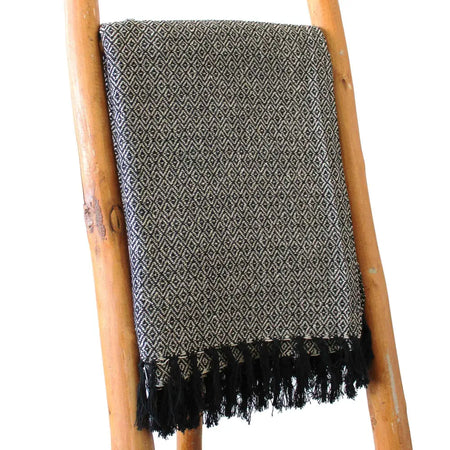 A textured black and gray cotton comfort throw with a diamond pattern and black fringe, a versatile piece for any space