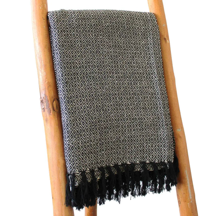 A textured black and gray cotton comfort throw with a diamond pattern and black fringe, a versatile piece for any space