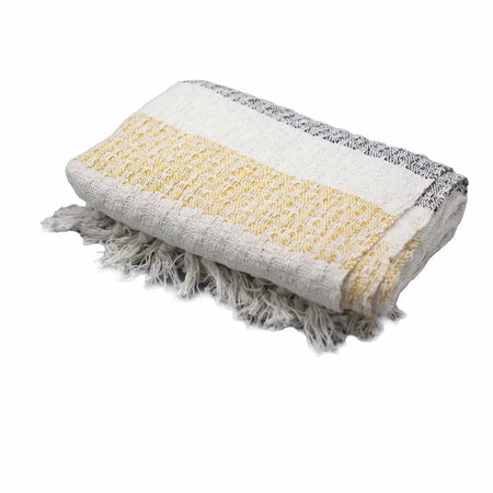 A folded cotton comfort throw with cream pale yellow and gray stripes and fringed edges showing a woven texture