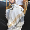 A cozy cotton throw blanket with wide diagonal stripes in cream mustard yellow and gray featuring fringed edges
