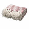 A cozy cotton throw blanket in cream and ruby with a speckled pattern and long off-white fringe