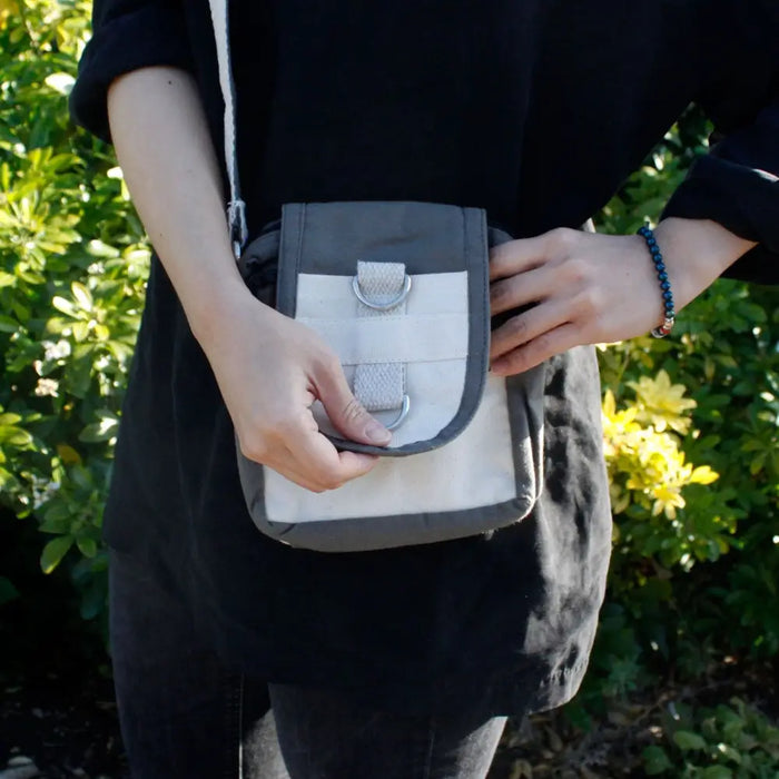 A compact cotton cross body bag in charcoal gray and white with durable fabric and metal d-ring closures