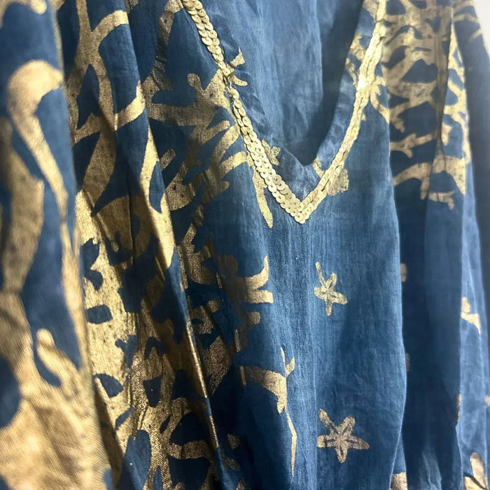 A navy blue cotton kaftan with gold foil patterns and a gold sequin trim along the linen neckline