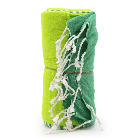 A rolled-up cotton pario towel in lime green and teal with white tassels suitable for picnics