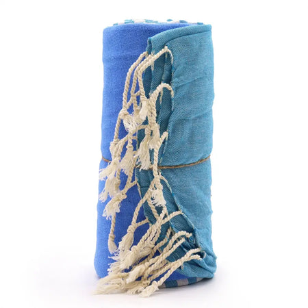 A rolled-up sky blue cotton pario towel with cream tassels and woven texture