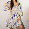 A white cotton print dress with v-neckline featuring blue and gold evil eye and elephant embroidery patterns