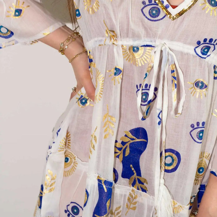 A sheer white cotton print dress with embroidered blue and gold evil eye motifs and leaf patterns in medium large size