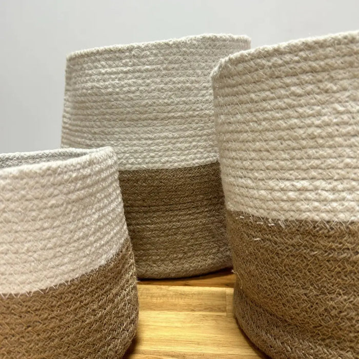 Three cotton rope storage baskets with a white upper half and natural brown lower half in a set of 3 rope storage baskets