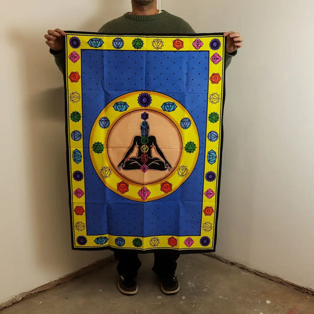 Blue cotton wall tapestry with meditating figure and rainbow chakra symbols framed by yellow geometric floral border
